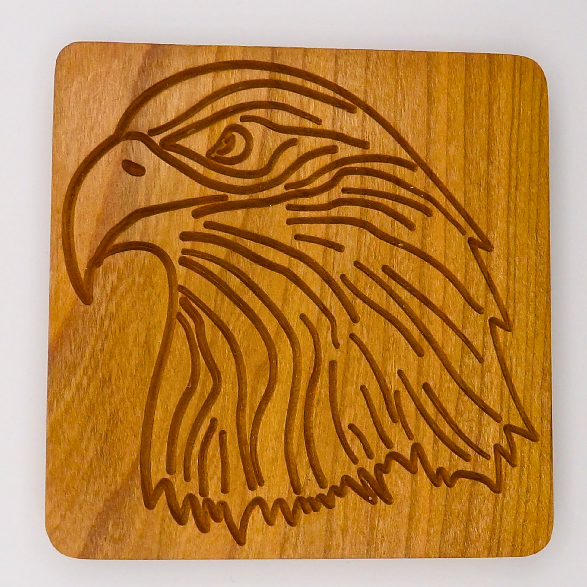 Wooden coaster with an engraved eagle design on a white background