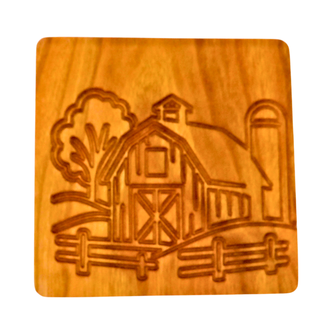 Wooden coaster with engraved design of a barn and trees