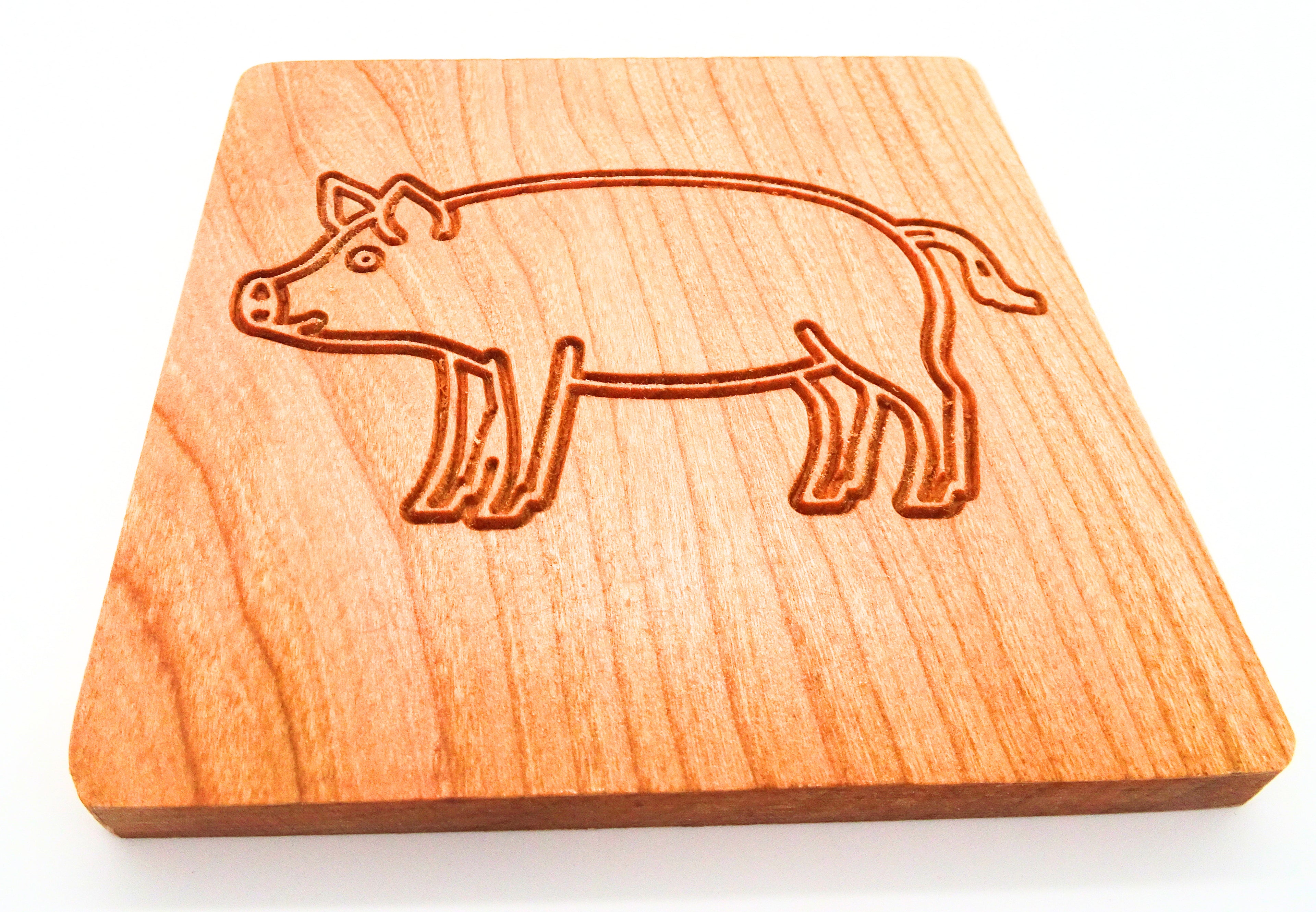 Square cherry wooden coaster with a pig design engraved on it