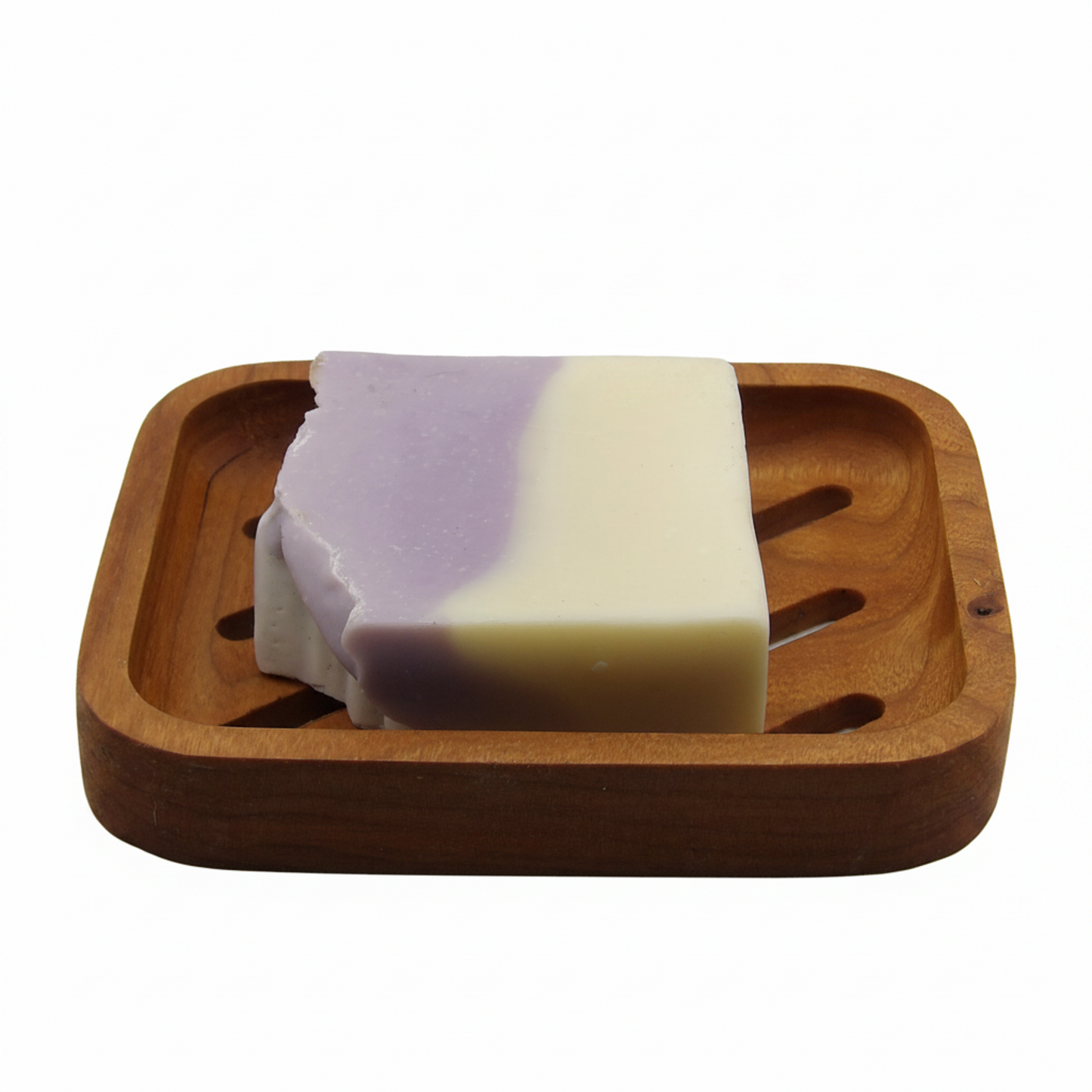 A rectangular bar of soap with a lavender-purple and cream color split, resting on a square wooden soap dish against a plain white background.